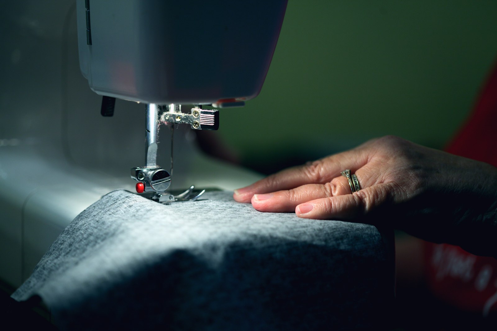 Tailor's hands guiding fabric through a sewing machine